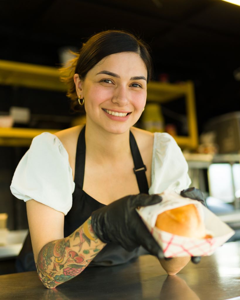 woman working in restaurant holding hamburger on tra